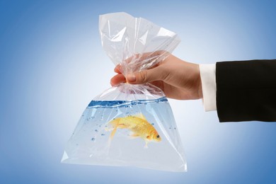 Woman holding plastic bag with fish and water on blue gradient background, closeup