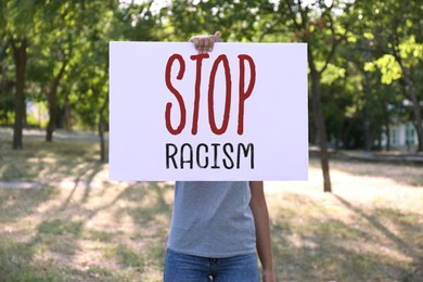 Image of Woman holding poster with text Stop Racism outdoors