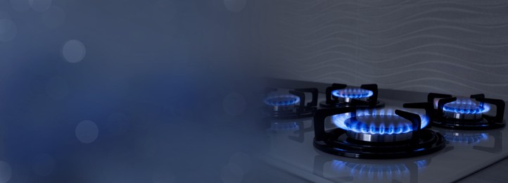 Image of Gas burners with blue flame on stove, closeup. Banner design with space for text