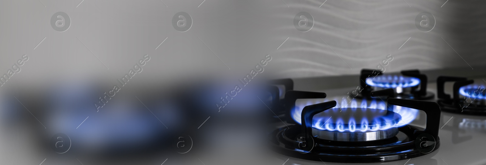 Image of Gas burners with blue flame on stove, closeup. Banner design with space for text