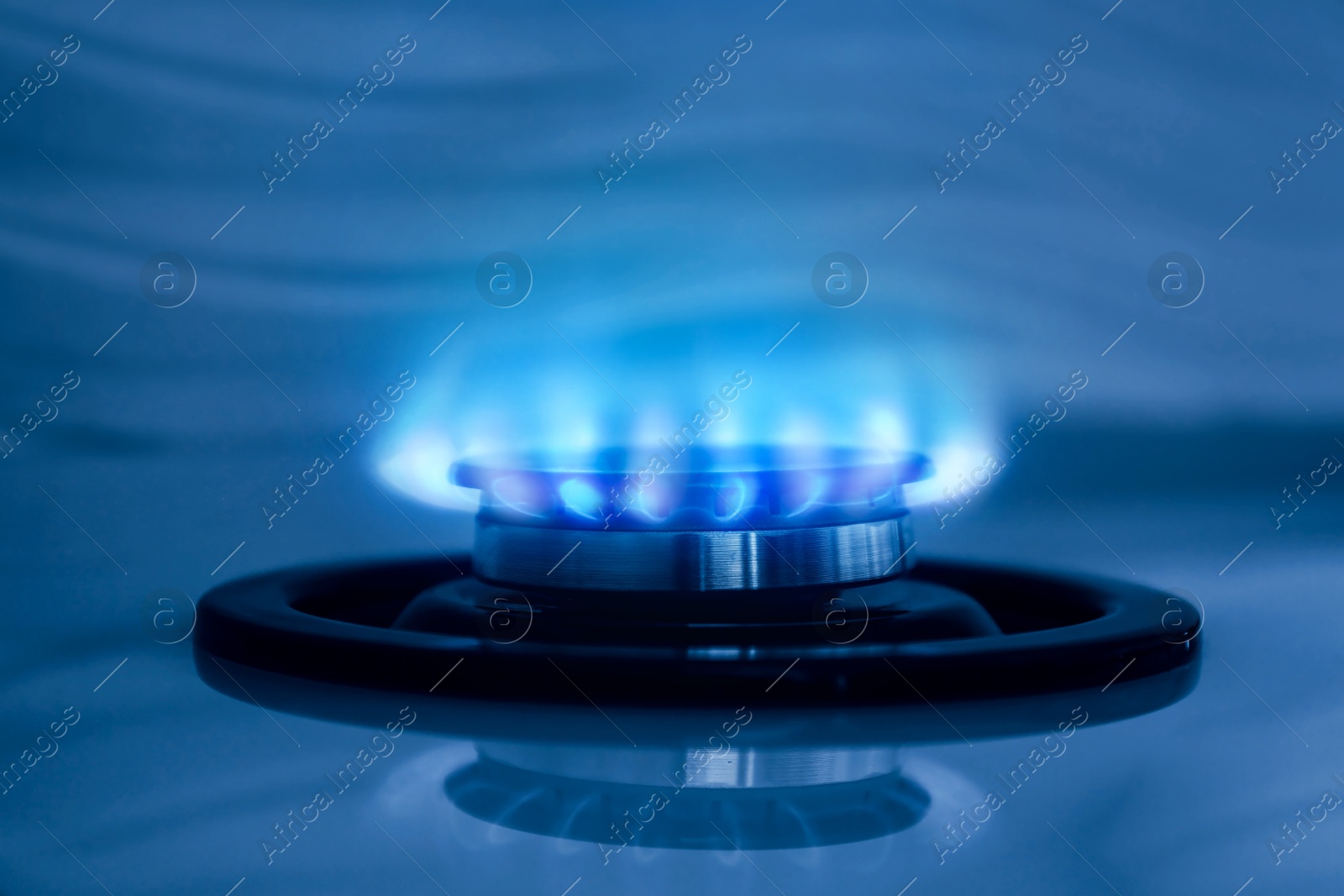 Image of Gas burner with blue flame on stove, closeup