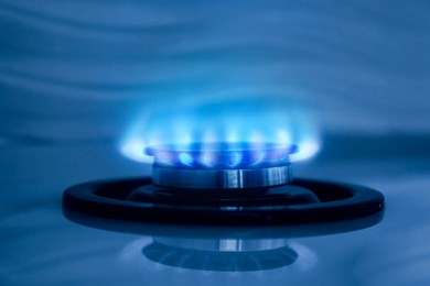 Image of Gas burner with blue flame on stove, closeup