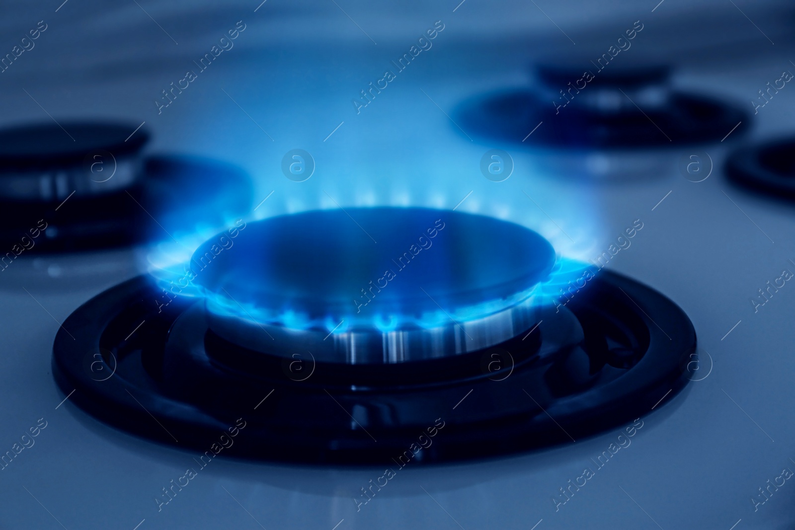 Image of Gas burner with blue flame on stove, closeup