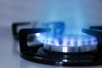 Image of Gas burner with blue flame on stove, closeup