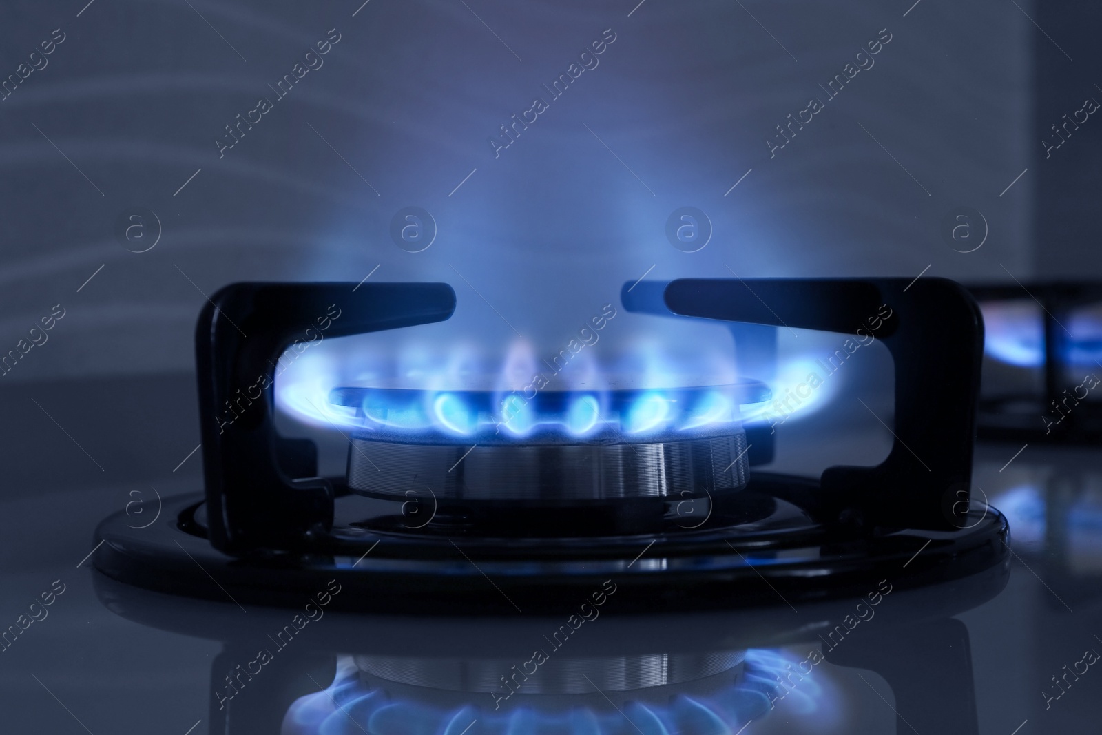 Image of Gas burner with blue flame on stove, closeup