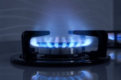 Image of Gas burner with blue flame on stove, closeup