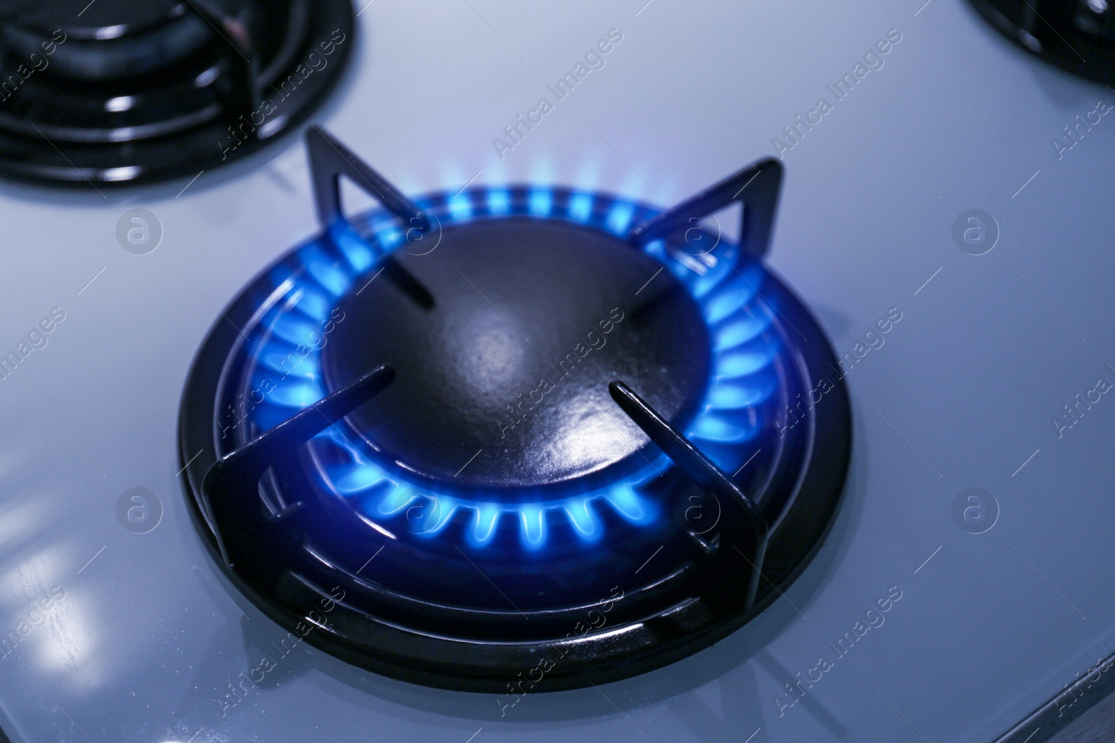 Image of Gas burner with blue flame on stove, closeup