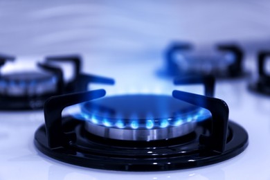 Image of Gas burner with blue flame on stove, closeup