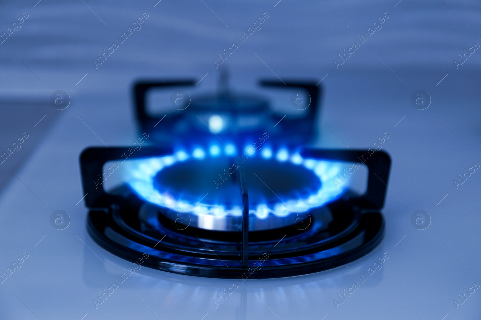 Image of Gas burner with blue flame on stove, closeup