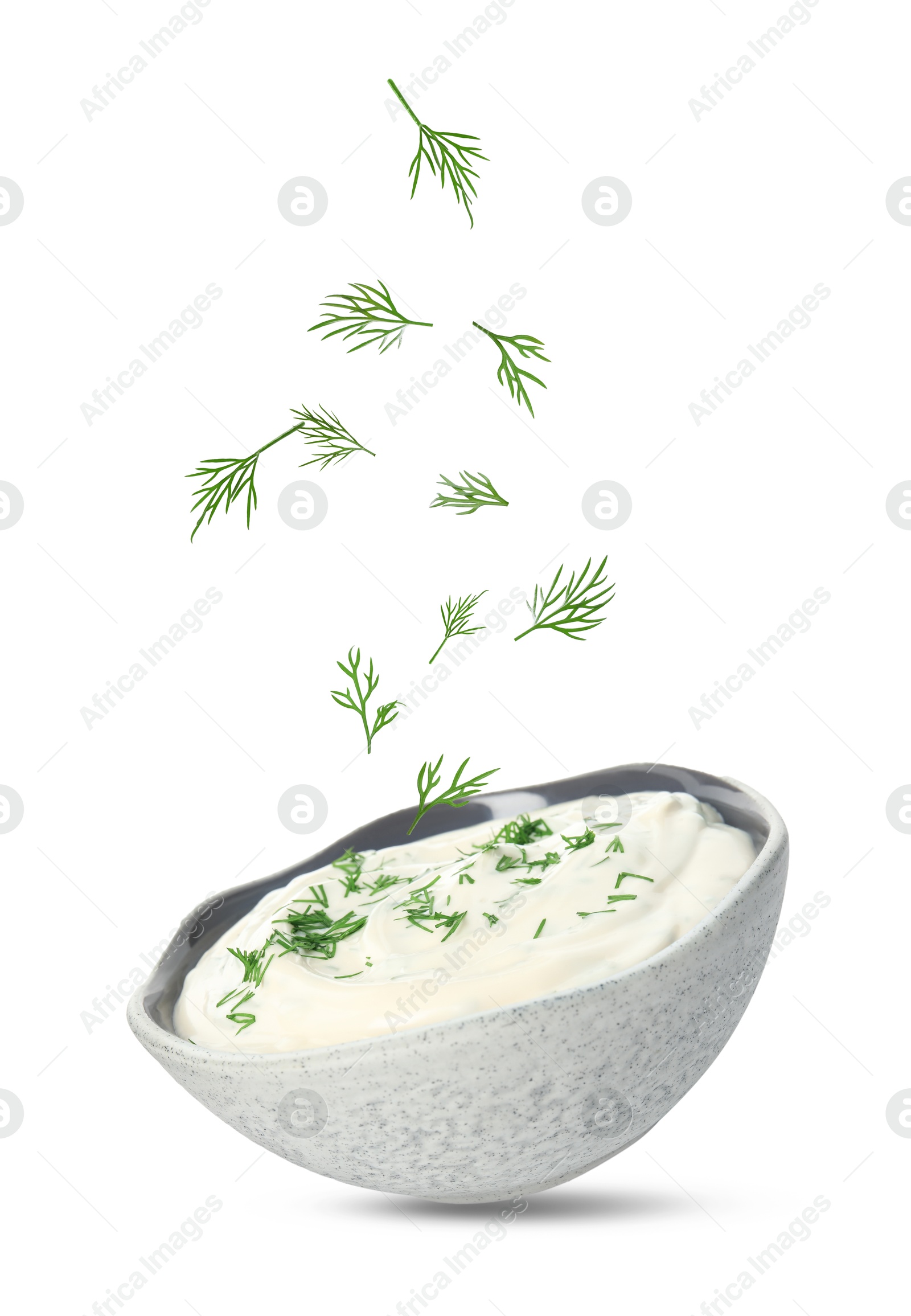 Image of Fresh green dill falling into bowl of sauce on white background