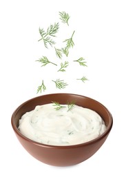 Image of Fresh green dill falling into bowl of sauce on white background