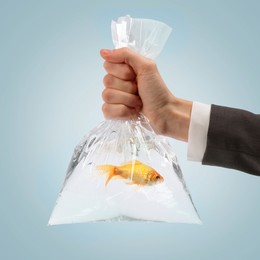 Woman holding plastic bag with fish and water on grey gradient background, closeup