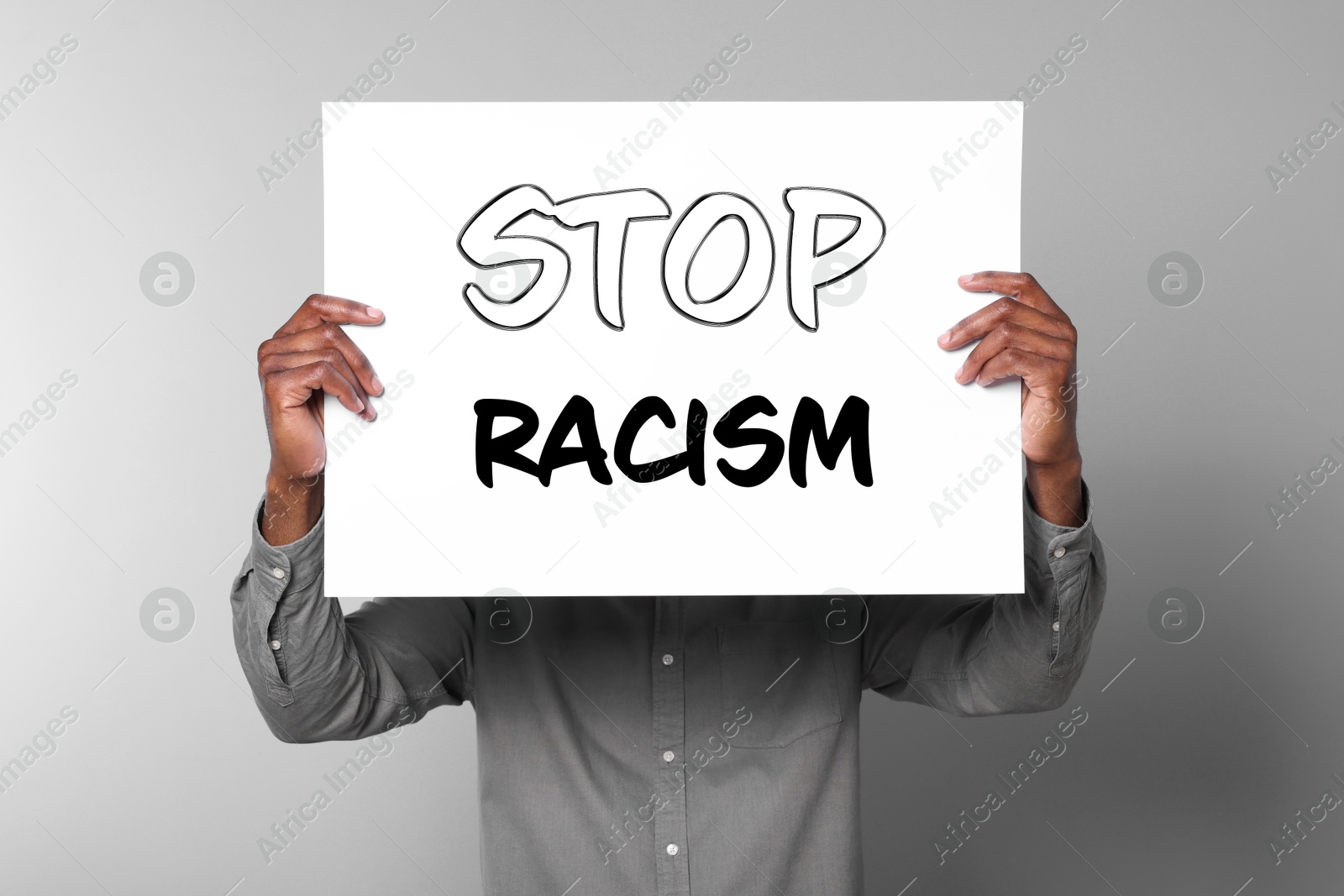 Image of Man holding paper with text Stop Racism on grey background, closeup