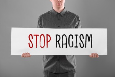 Image of Man holding paper with text Stop Racism on grey background, closeup