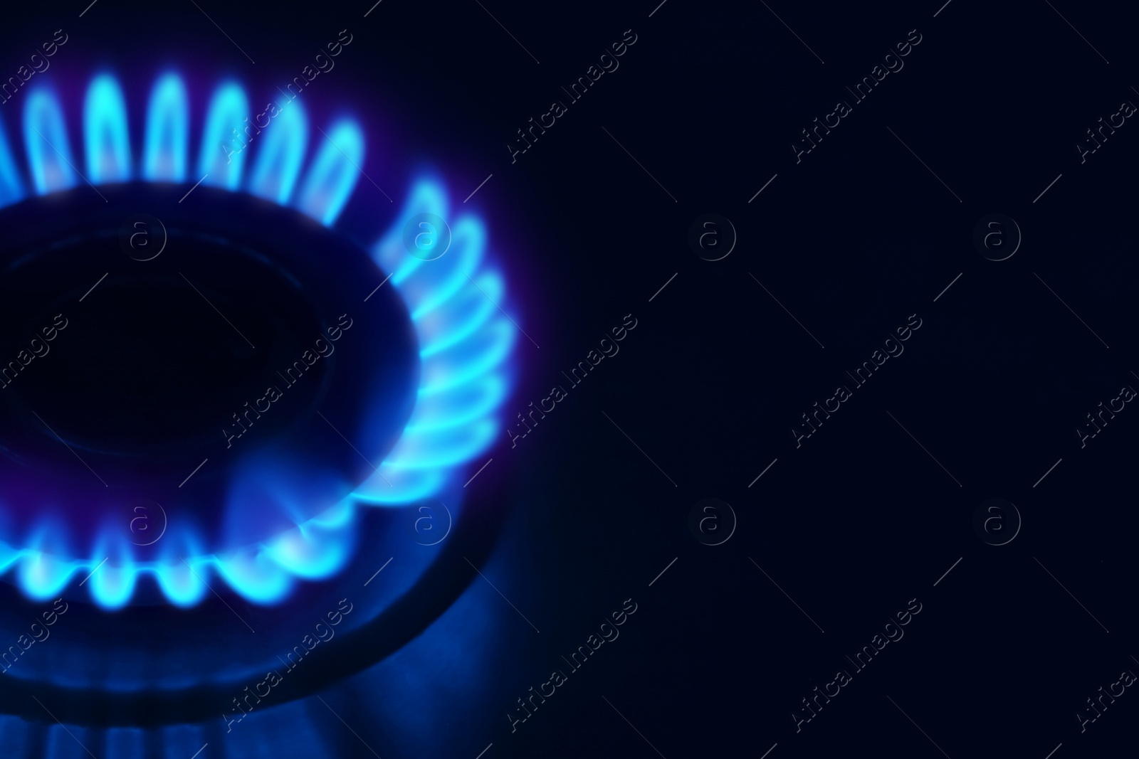 Image of Gas burner with blue flame on stove, closeup. Space for text