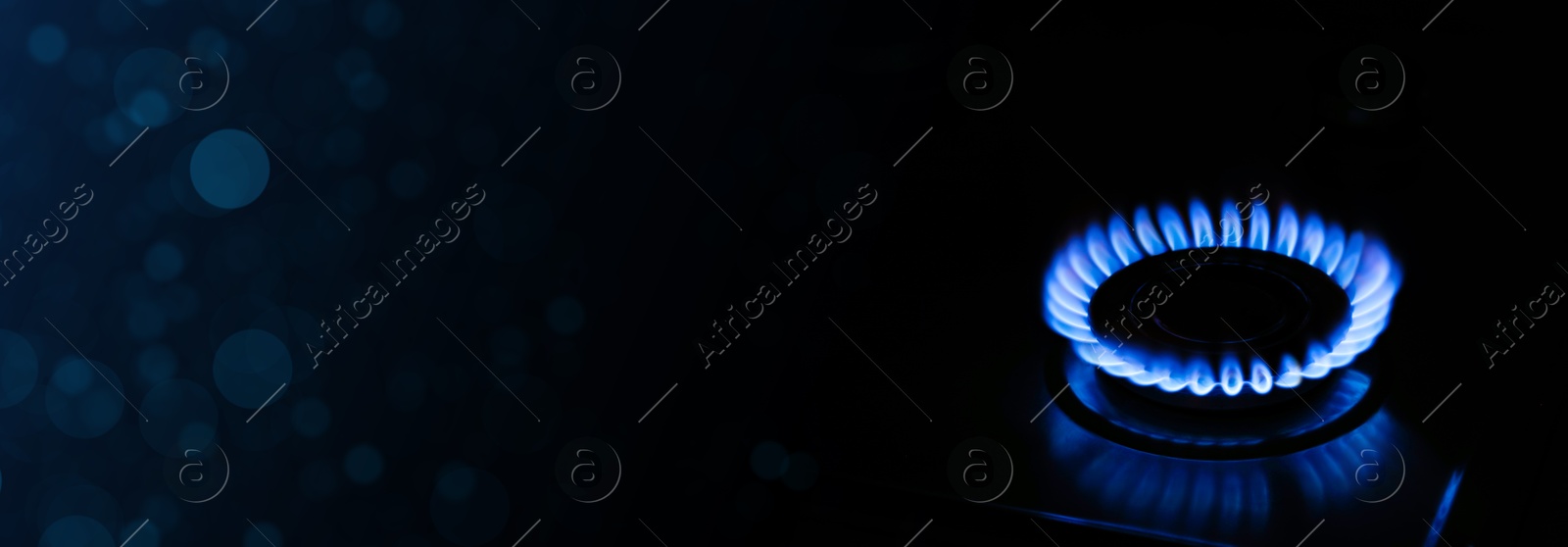 Image of Gas burner with blue flame on stove in darkness, closeup. Banner design with space for text