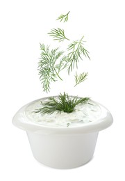 Image of Fresh green dill falling into bowl of sauce on white background