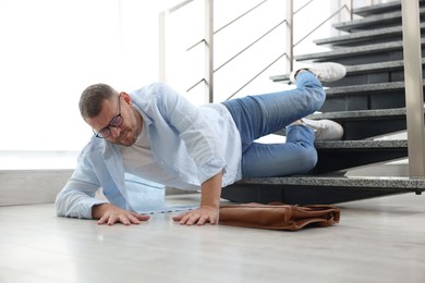 Photo of Injured man on stairs in building after fall. Dangerous accident