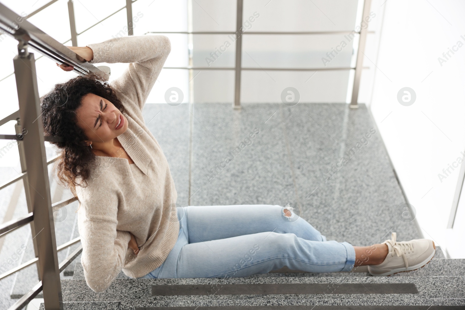 Photo of Injured woman on stairs in building after fall. Dangerous accident