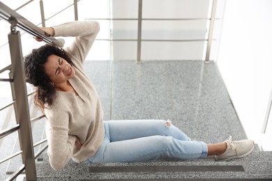 Photo of Injured woman on stairs in building after fall. Dangerous accident