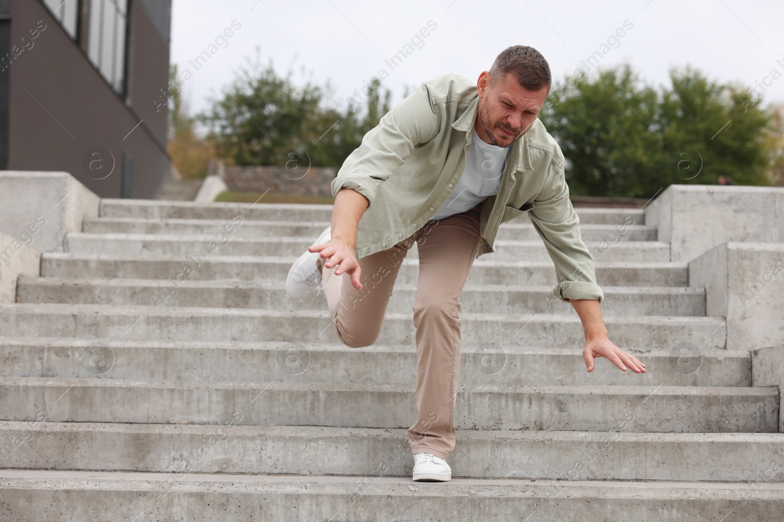 Photo of Man falling on stairs outdoors. Dangerous accident