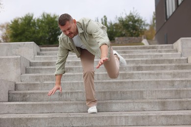 Photo of Man falling on stairs outdoors. Dangerous accident