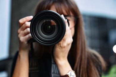 Photo of Professional photographer taking picture with camera outdoors, selective focus