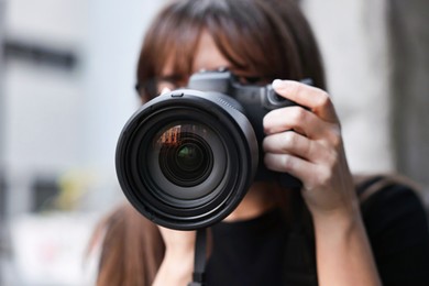 Photo of Professional photographer taking picture with camera outdoors, selective focus