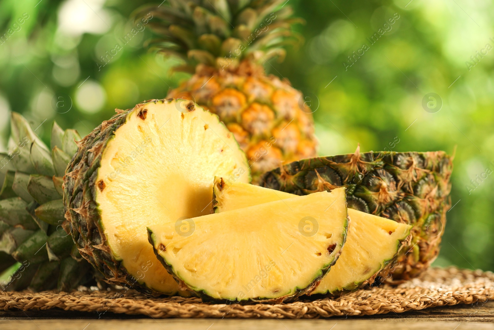 Photo of Fresh ripe pineapples on wooden table against blurred background, closeup