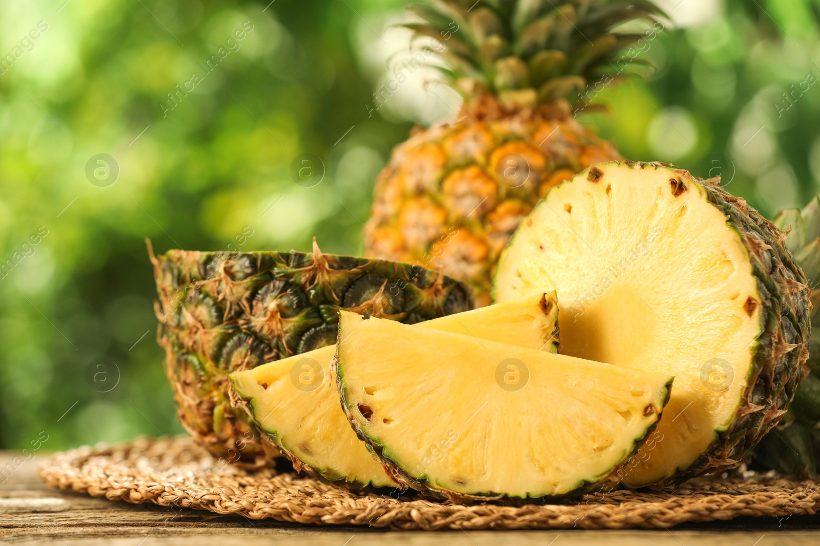 Photo of Fresh ripe pineapples on wooden table against blurred background, closeup