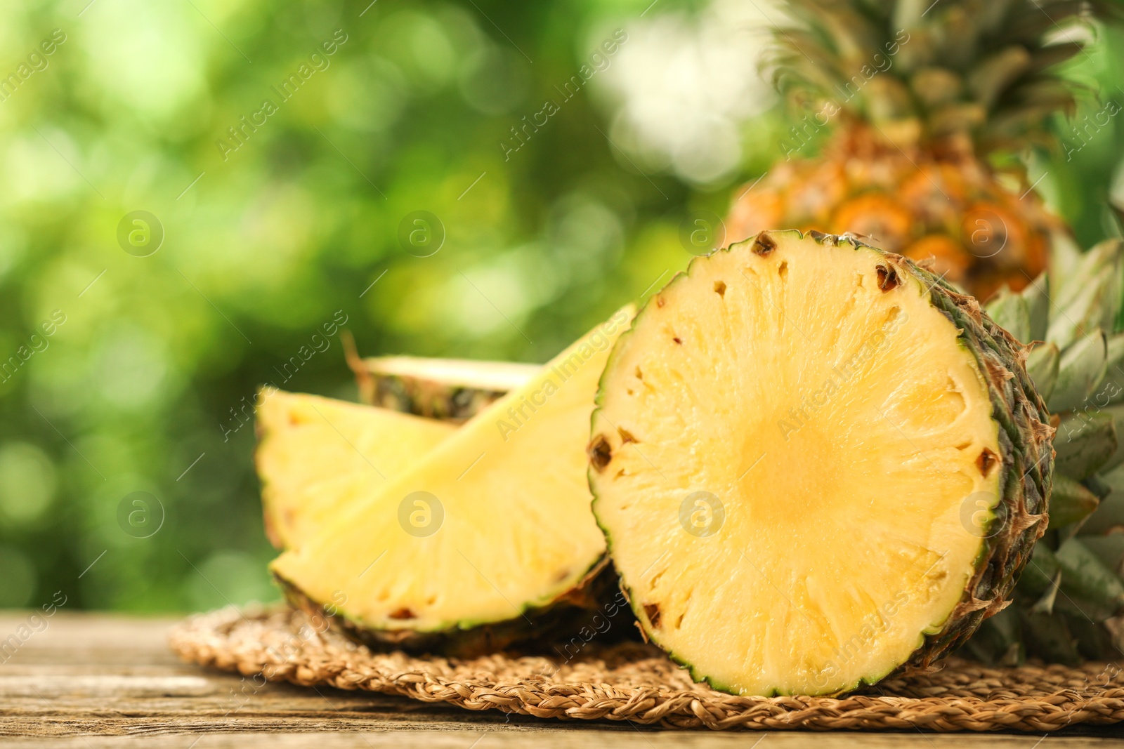 Photo of Fresh ripe pineapples on wooden table against blurred background, closeup