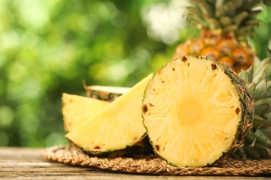 Fresh ripe pineapples on wooden table against blurred background, closeup