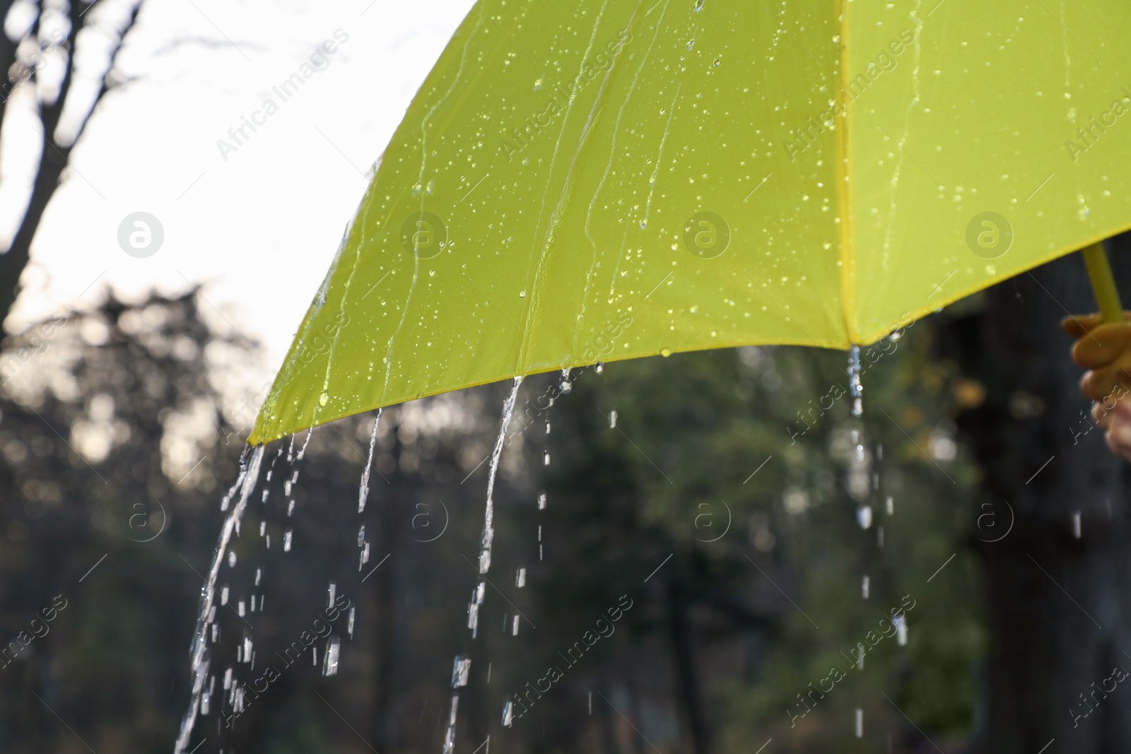 Photo of Open yellow umbrella under pouring rain outdoors, closeup