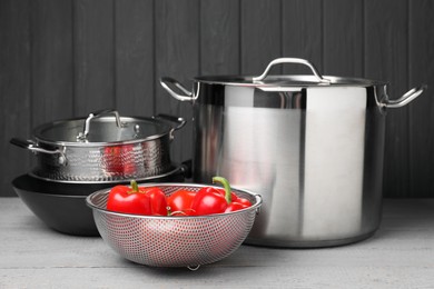 Photo of Stainless steel dishware and vegetables on grey wooden table