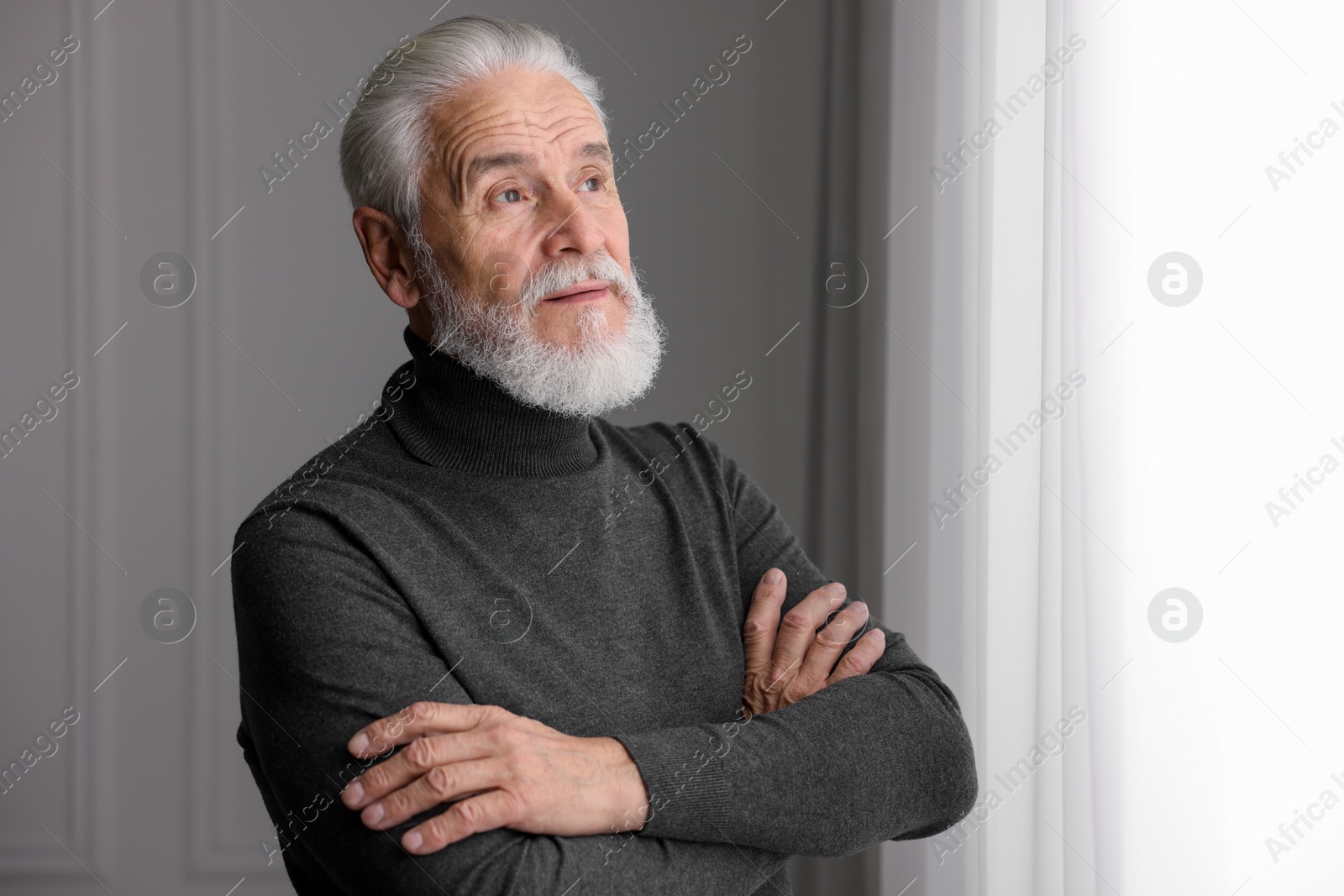 Photo of Portrait of handsome bearded man near window indoors