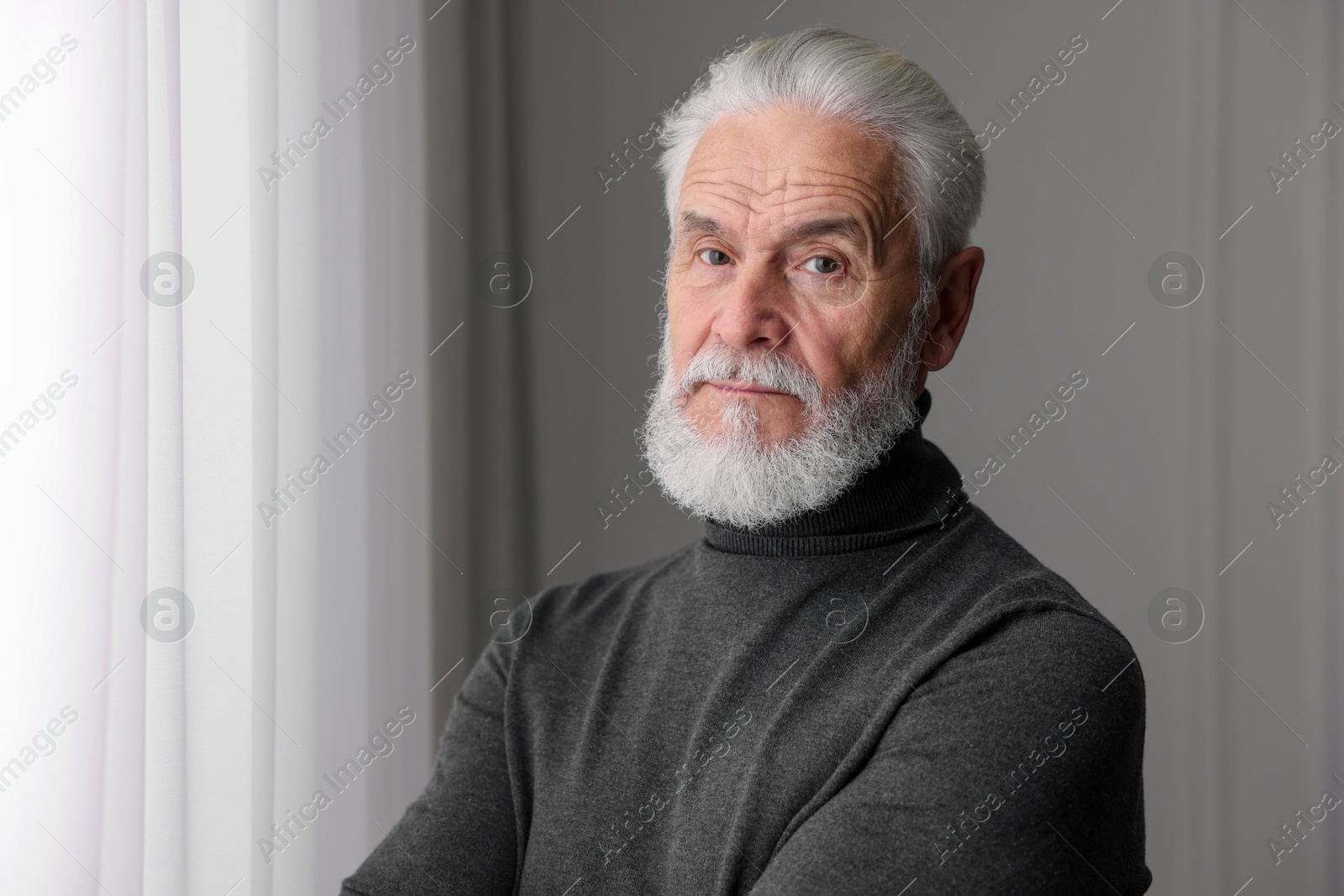 Photo of Portrait of handsome bearded man near window indoors