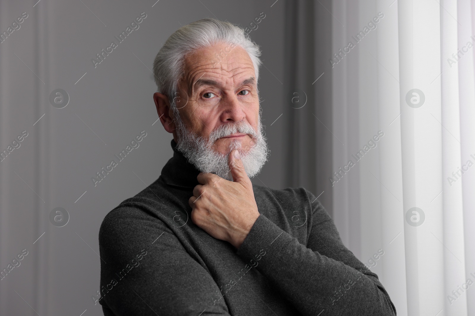 Photo of Portrait of handsome bearded man near window indoors