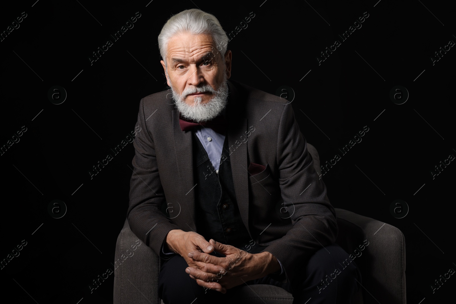 Photo of Portrait of serious senior man with silver beard on black background