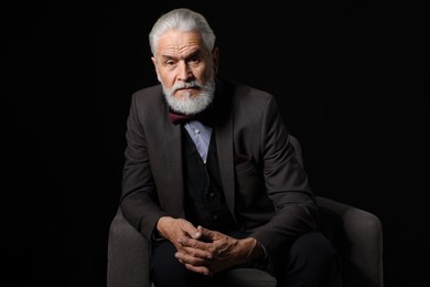 Photo of Portrait of serious senior man with silver beard on black background