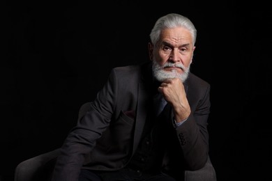 Photo of Portrait of serious senior man with silver beard on black background