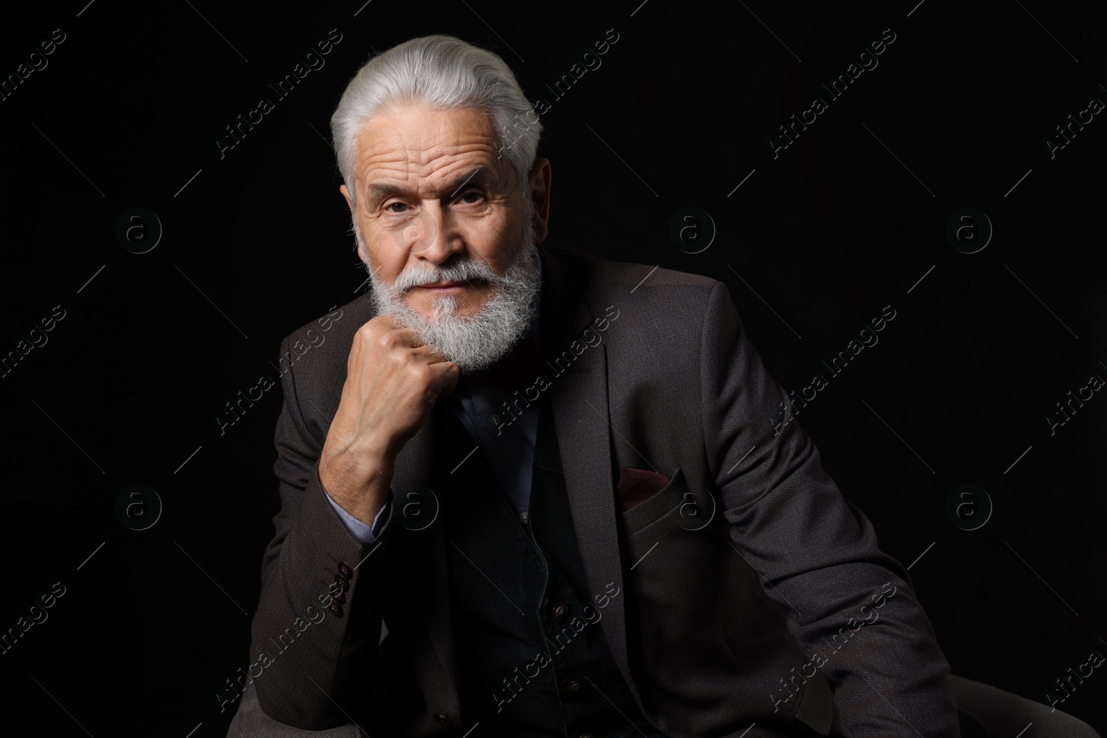 Photo of Portrait of serious senior man with silver beard on black background