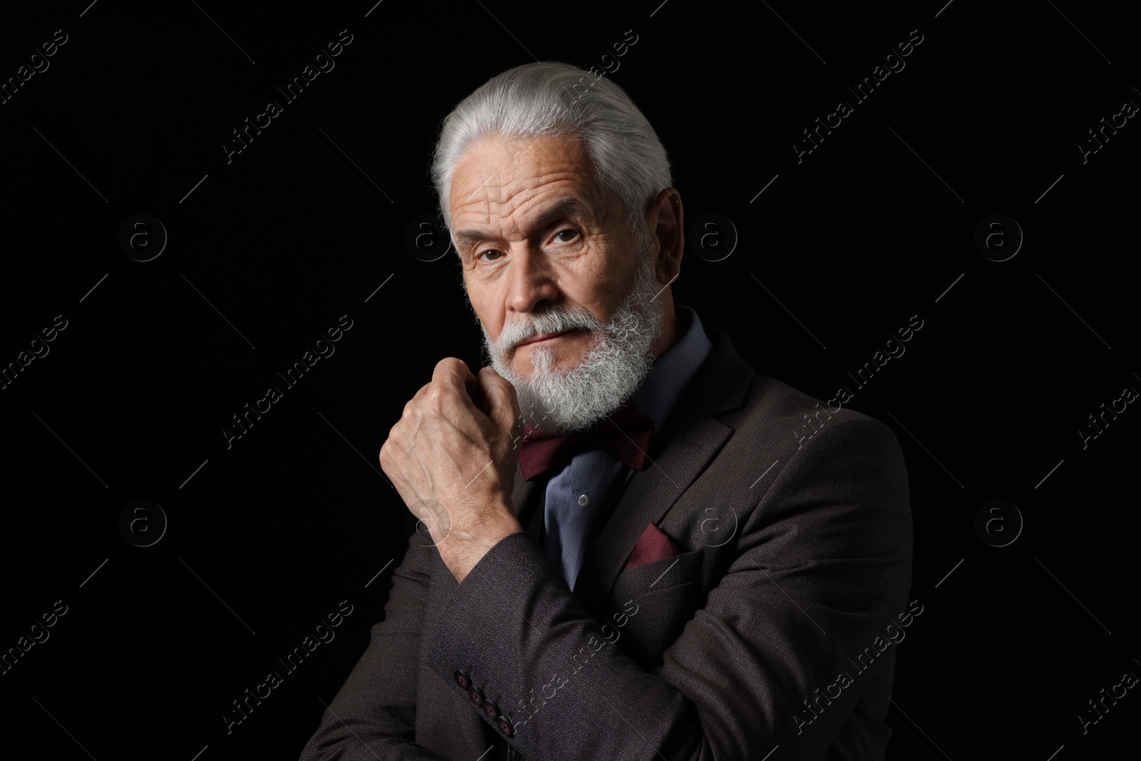 Photo of Portrait of serious senior man with silver beard on black background