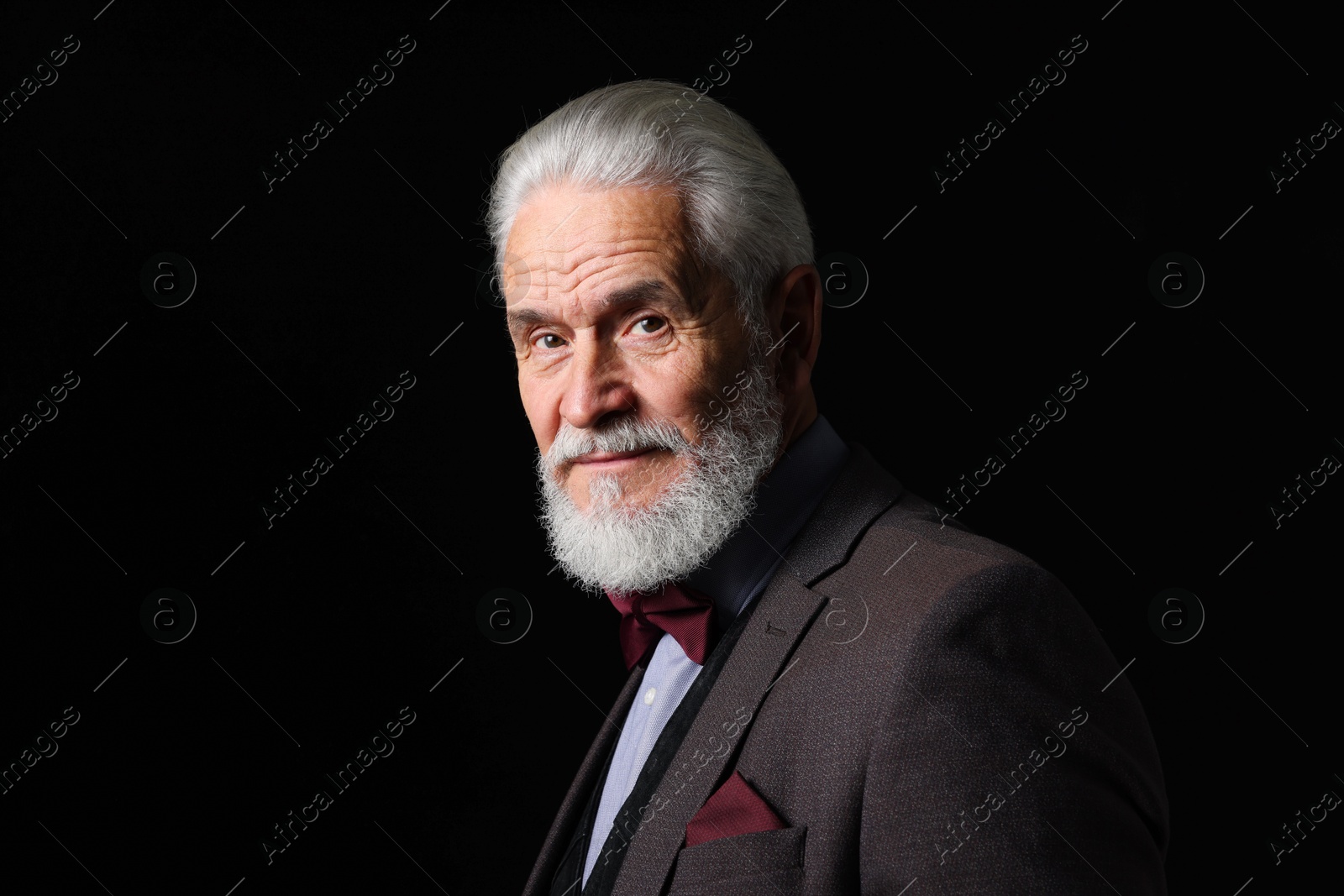 Photo of Portrait of serious senior man with silver beard on black background