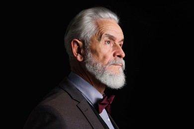 Photo of Portrait of serious senior man with silver beard on black background