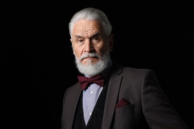 Photo of Portrait of serious senior man with silver beard on black background