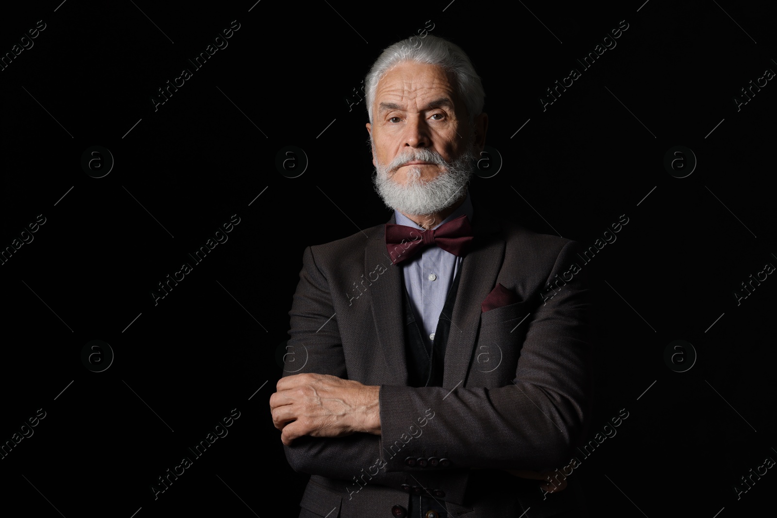 Photo of Portrait of serious senior man with silver beard on black background