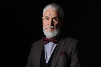 Photo of Portrait of serious senior man with silver beard on black background