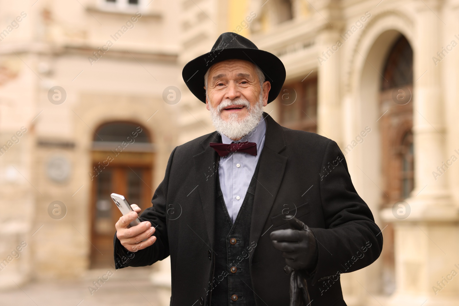 Photo of Elegant senior man with smartphone on city street