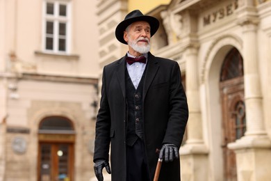 Photo of Elegant senior man with walking cane on city street