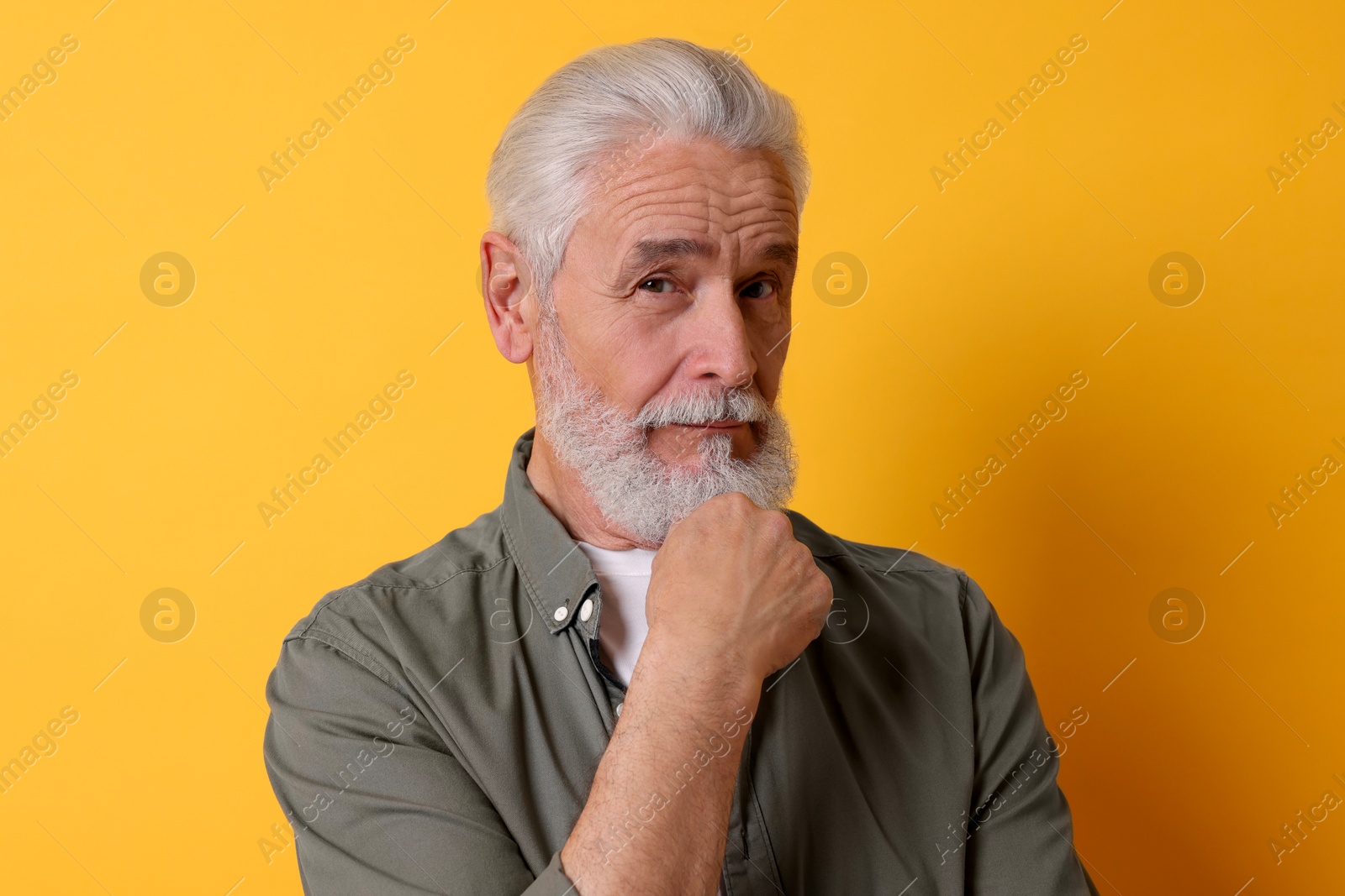 Photo of Portrait of senior man with gray beard on orange background